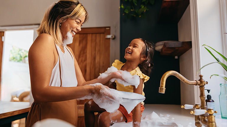 woman and child washing dishes in the sink